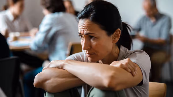 Adult showing hunched posture and lowered gaze associated with low self-esteem